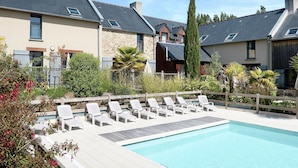 A pool area with lounge chairs and a stone building in the background.