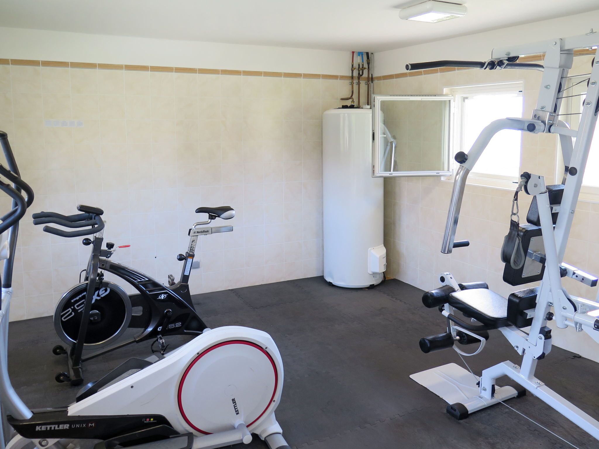 A gym with a stationary bike, an elliptical trainer, and a weight machine.