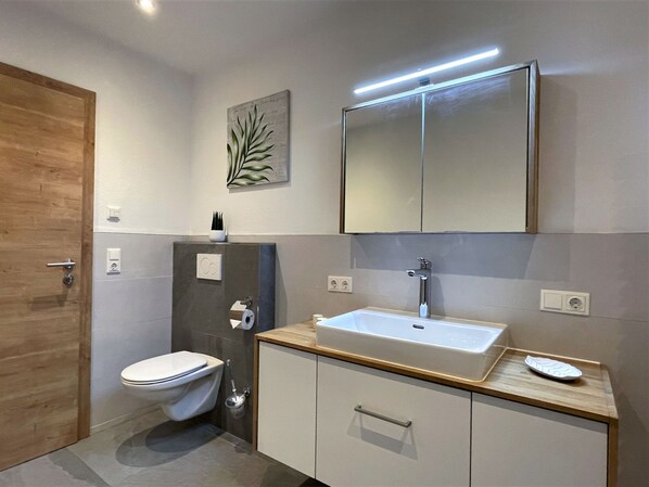 A modern bathroom with a toilet, sink, and mirror.