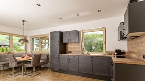 A modern kitchen with dark cabinets, a wooden countertop, and a large window.