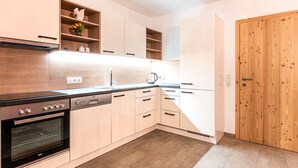 Una cocina moderna con armarios de madera, horno integrado y puerta de madera.