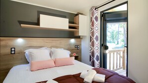 A bedroom with a bed, pillows, a blanket, a bedside table, and a view of the outdoors through a door.