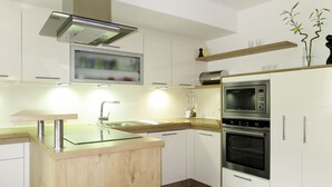 Eine moderne Küche mit weißen Schränken, einer Holz Arbeitsplatte, einem Einbauofen und einer Mikrowelle.