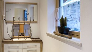 Ein Badezimmer mit Spiegel, einem Waschbecken mit Holzauszug, einem Fenster mit einer Kakteenpflanze und einem Regal mit einem Topfpflanzen.