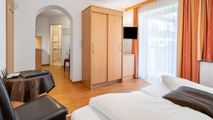 A hotel room with a bed, a desk with a chair, a wardrobe, and a TV mounted on the wall. - Apartment Rosa by Interhome (Mayrhofen)