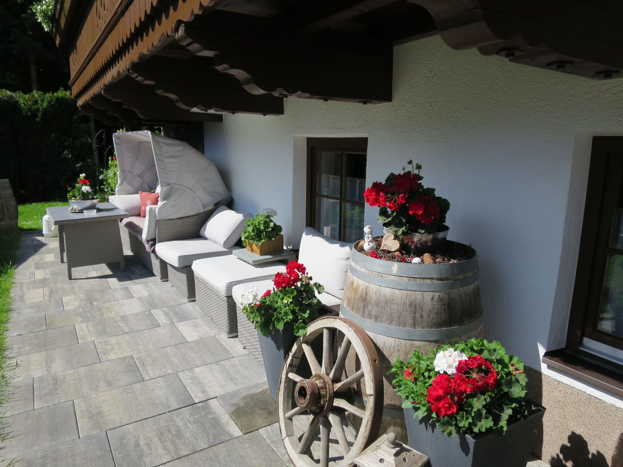 An outdoor seating area with a wicker sofa, a small table, and potted plants.