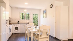 Cocina compacta con comedor, que incluye lavadora, horno y mesa con sillas.