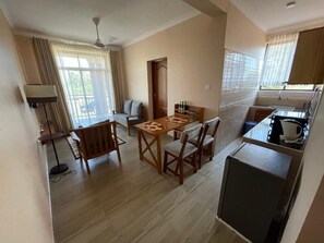A compact living space with a dining area, a kitchenette, and a small seating area. - D&D Apartments (Moshi)