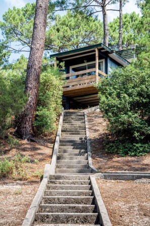 A staircase leading to a wooden deck with a house in the background.
