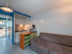 A compact living space with a kitchenette, a sofa, and a wooden table.