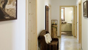 Un pasillo con puertas de madera, un banco y un cuadro en la pared.