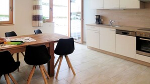 Una cocina moderna con una mesa y sillas de madera, una cafetera y un lavavajillas.