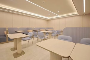 Un comedor moderno y bien iluminado con asientos tipo cabina y mesas, que presenta un diseño limpio y minimalista.