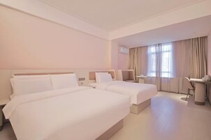 A hotel room with two beds, a desk, and a chair.