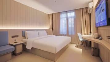 A modern hotel room with a large bed, bedside tables, a desk, and a television.