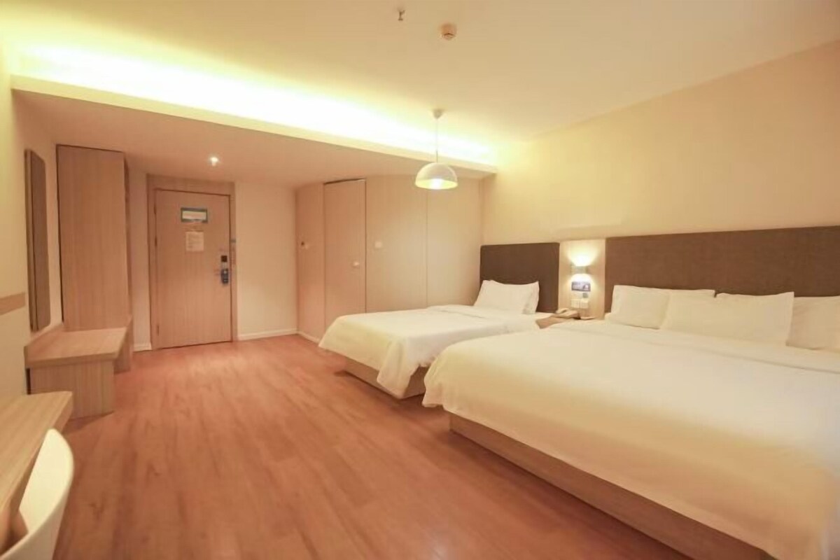 A hotel room with two beds, a desk, and a wardrobe.