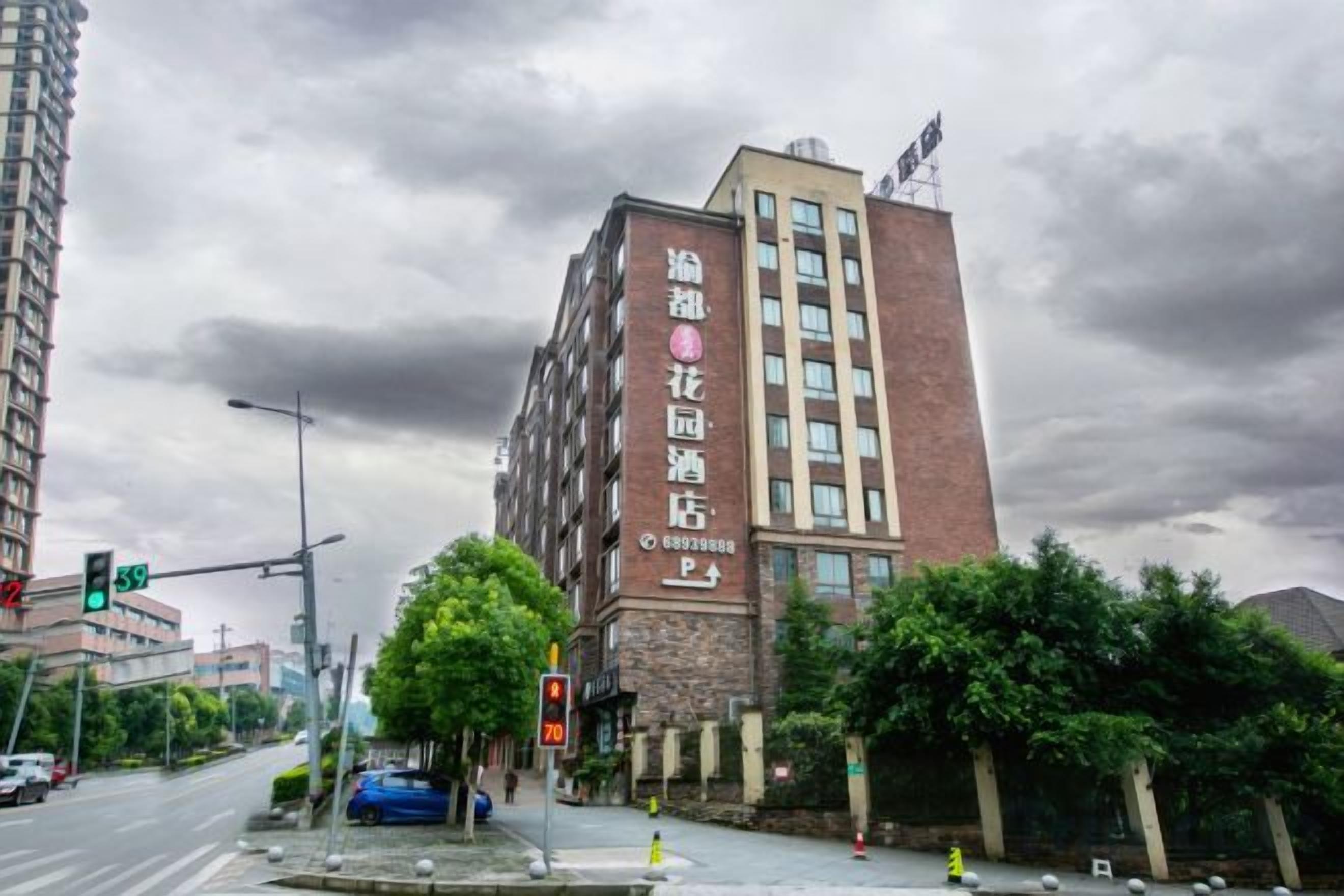 A multi-story building with a prominent sign on the facade, a traffic light, and a blue car parked on the street.