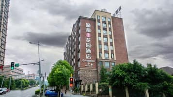 A multi-story building with a prominent sign on the facade, a traffic light, and a blue car parked on the street.