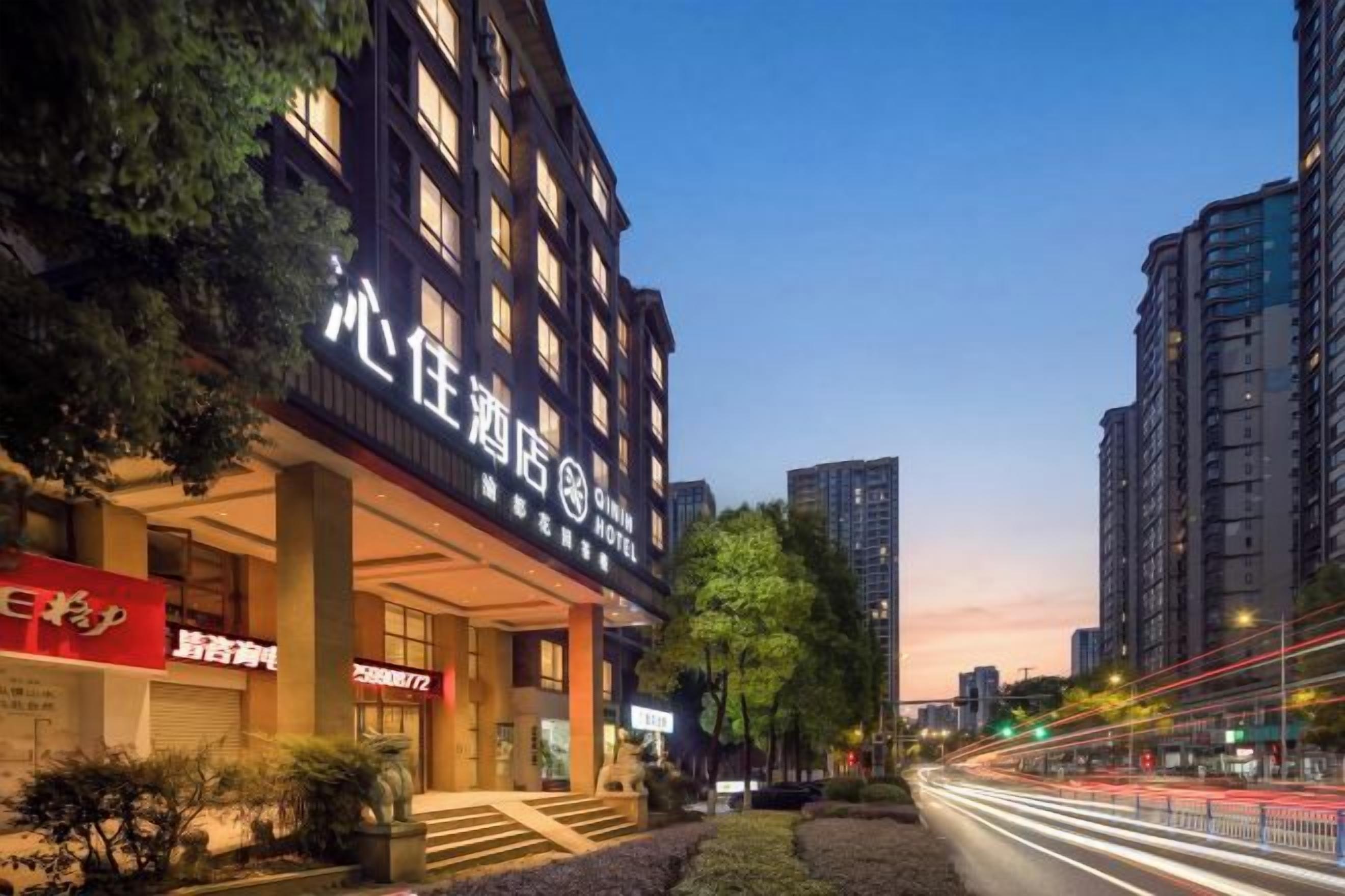 Un hotel con fachada moderna, entrada visible y un área exterior bien cuidada con escalones que conducen a la entrada.