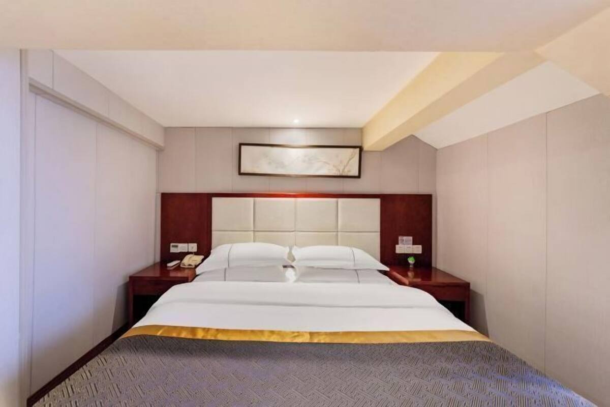 A hotel room with a bed, bedside tables, a telephone, and a framed picture on the wall.
