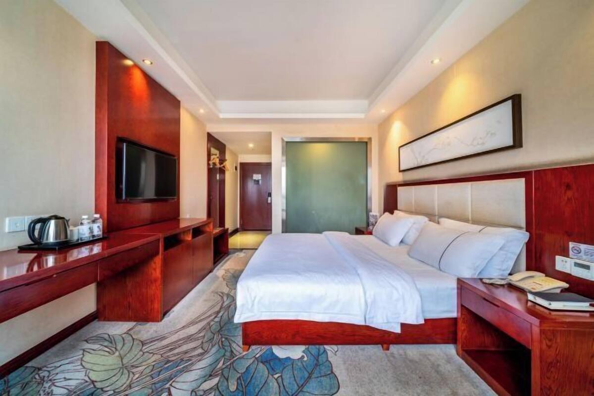 A hotel room with a large bed, a TV, a desk, and a chair.