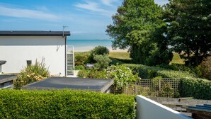 Un quartier résidentiel offrant une vue sur la plage, un bâtiment blanc avec un toit noir et une végétation luxuriante.