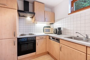 A kitchen with wooden cabinets, a stove, a microwave, and a sink.