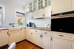 A kitchen with white cabinets, a black oven, and a window with a view of a brick building.