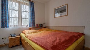 Une chambre à coucher avec un lit, une table de chevet, une lampe et un tableau encadré au mur.