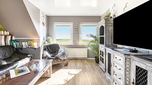 Un salon moderne avec un canapé, une table basse, un téléviseur et des étagères.