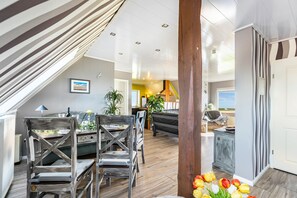 A modern interior with a dining area, wooden chairs, a sofa, and a view of the outdoors. - Apartment "Hafenblick" with Sea View, Private Terrace & High-Speed Wi-Fi (Oland)