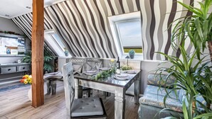 Un espace repas avec une table en bois, des chaises et une vue par la fenêtre.