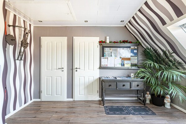 A hallway with two white doors, a desk with papers, a potted plant, and a striped wall. - Apartment "Hafenblick" with Sea View, Private Terrace & High-Speed Wi-Fi (Oland)