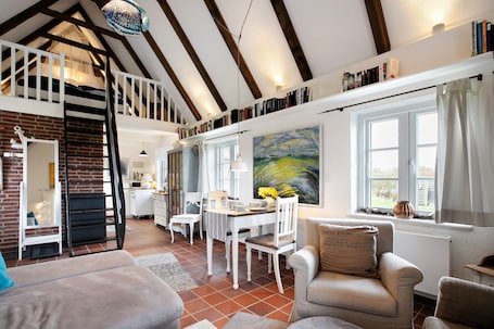 A spacious loft-style living area with a dining table, chairs, and a cozy seating area.. Holiday Apartment 'Hyggelig Am Deich - Ockholm' with Private Terrace, Shared Garden & Wi-Fi