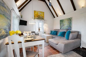 A cozy living room with a dining area, a sofa with blue cushions, and artwork on the walls. - Holiday Apartment 'Hyggelig Am Deich - Ockholm' with Private Terrace, Shared Garden & Wi-Fi (Ockholm)