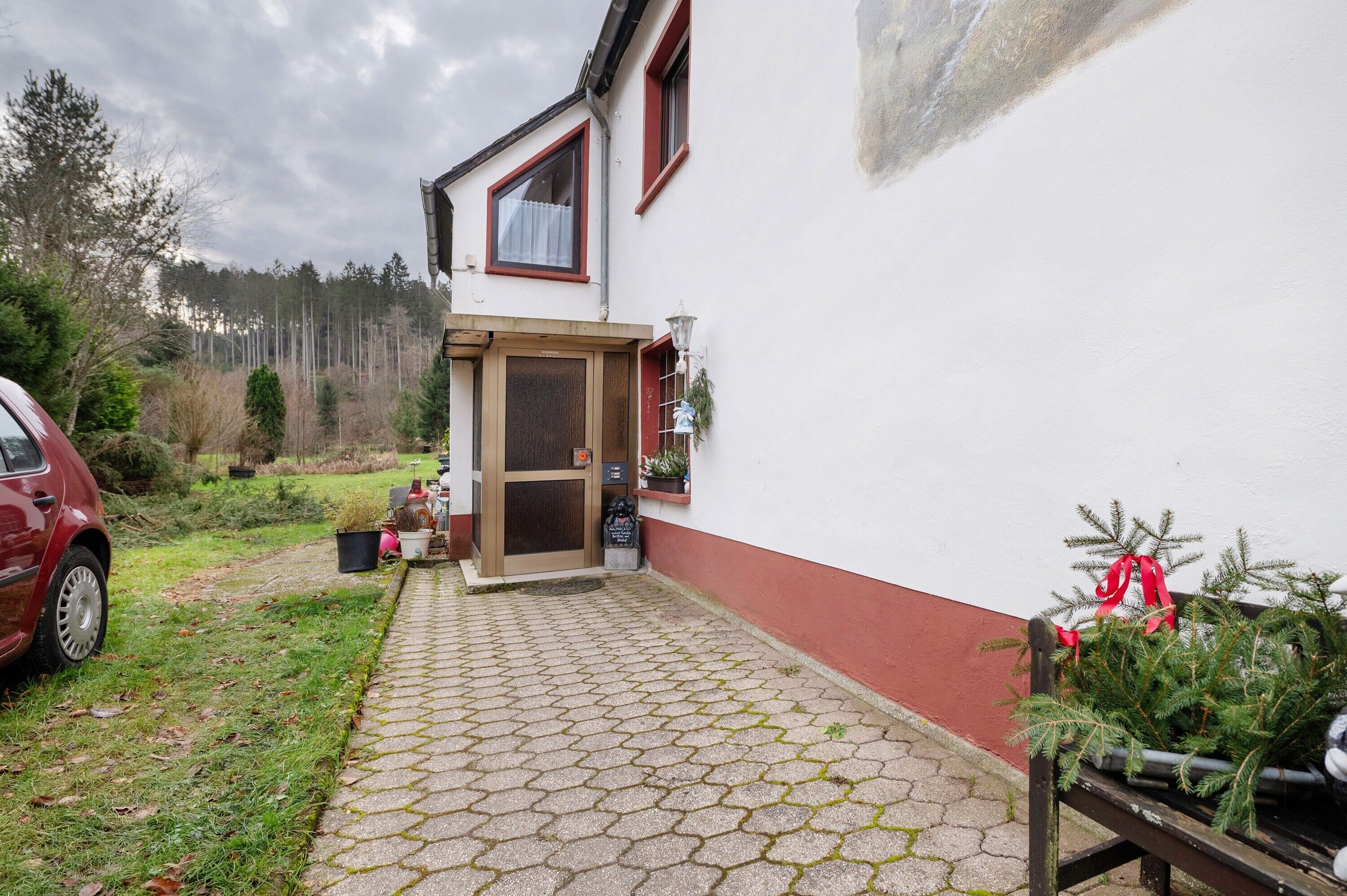 A building with a red door, a small porch, and a car parked outside.