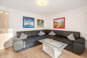 A modern living room with a grey sectional sofa, a white coffee table, and three framed artworks on the wall. - Apartment 'Haus Annenberg' with Shared Terrace, Shared Garden and Wi-Fi (Monzelfeld)