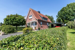 A red brick house with a sloped roof, a front porch, and a satellite dish.