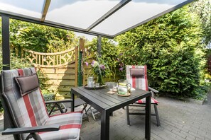 An outdoor patio with a table, chairs, and a garden view.