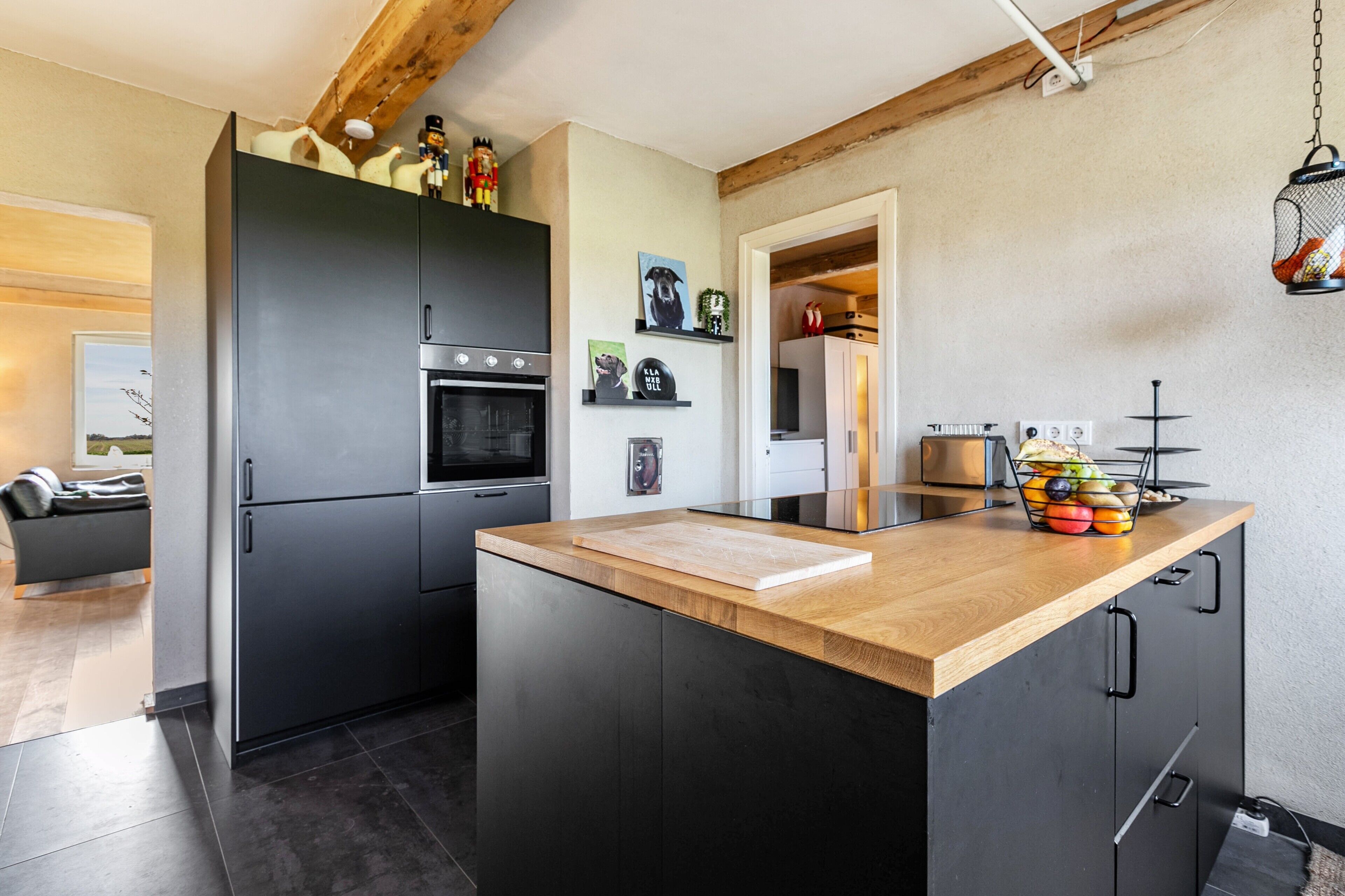 Una cocina moderna con una isla central, armarios oscuros y encimera de madera.