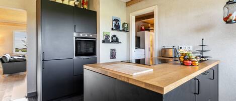 Una cocina moderna con una isla central, armarios oscuros y encimera de madera.