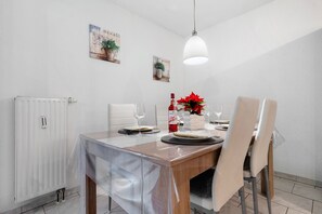 Un coin repas avec une table dressée pour quatre personnes, un radiateur blanc et deux œuvres d’art accrochées au mur.