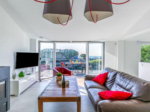A modern living room with a leather sofa, a wooden coffee table, and a TV on a white cabinet.