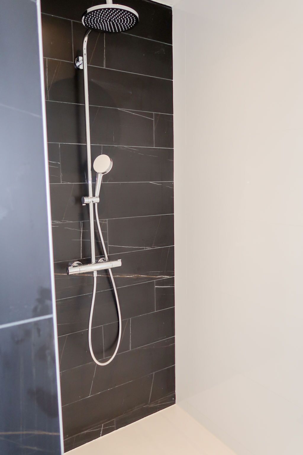 Um chuveiro moderno com chuveiro manual e painel de controle fixado na parede.