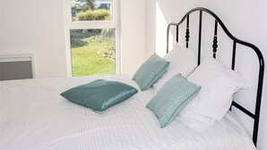 A bed with a view of a grassy area through a window. - La Ganivelle by Interhome (Kerlouan)