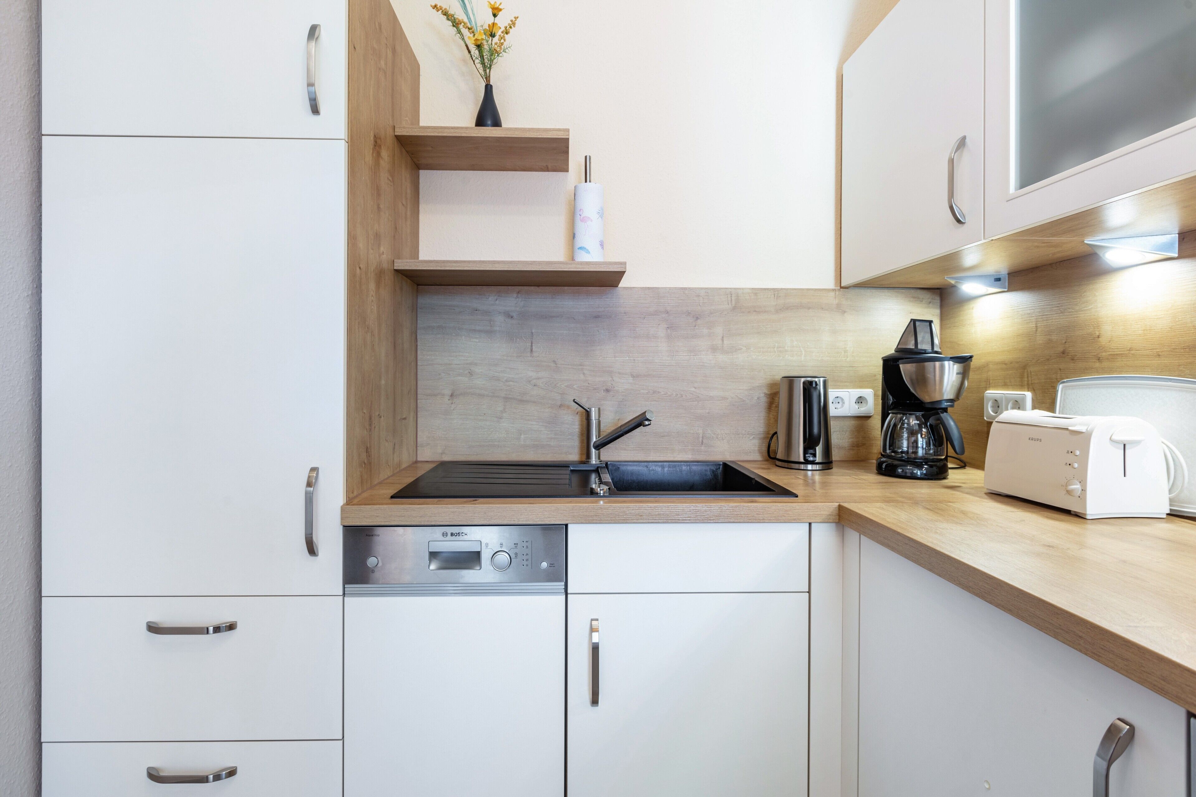 Una cocina moderna con lavavajillas integrado, cafetera y tostadora.