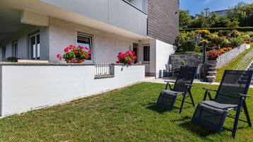 A modern building with a balcony, outdoor seating, and a well-maintained garden.