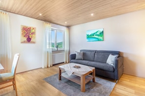 A living room with a sofa, a coffee table, a chair, and a painting on the wall.