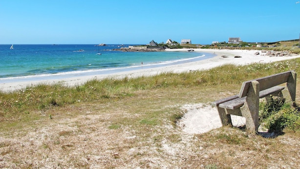 A beach with a bench, clear blue sky, and houses in the background. - Ty Louarn 1 by Interhome (Kerlouan)