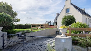 A gated entrance to a property with a number plaque '15', a paved pathway, and a garden area with a wooden fence. - Ty Louarn 1 by Interhome (Kerlouan)